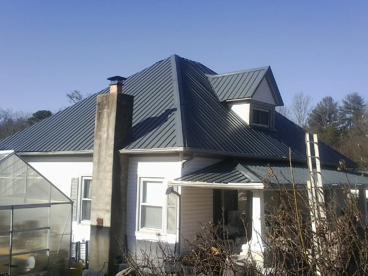 Dark blue standing seam metal roof on a white farmhouse with dormer — Slate & Tile Roof Repair by Roofing Brothers in Tarboro