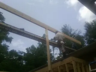Carpenter setting a ridge beam over a new addition frame — Ice Dam Removal by Roofing Brothers in Tarboro
