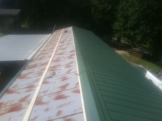 Old rusted panels beside newly installed green metal roofing — Wind Damage Roof Repair by Roofing Brothers in Tarboro