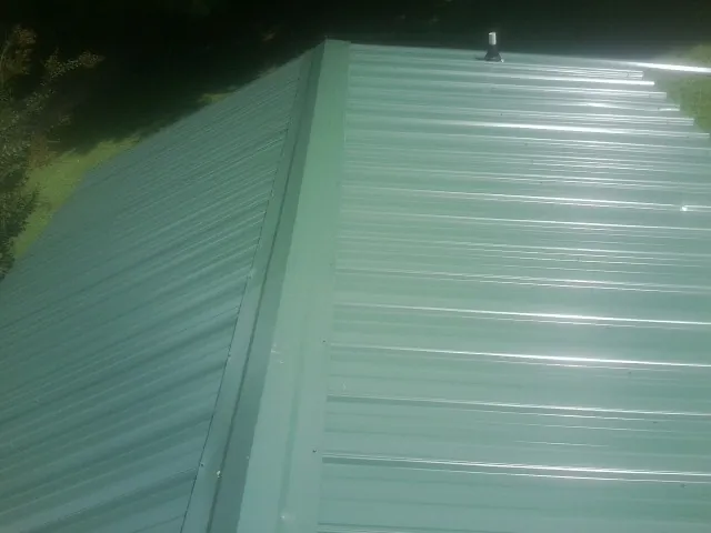 New green metal panels meeting at the ridge of a roof — Flat Roof Repair work by our crew in Tarboro