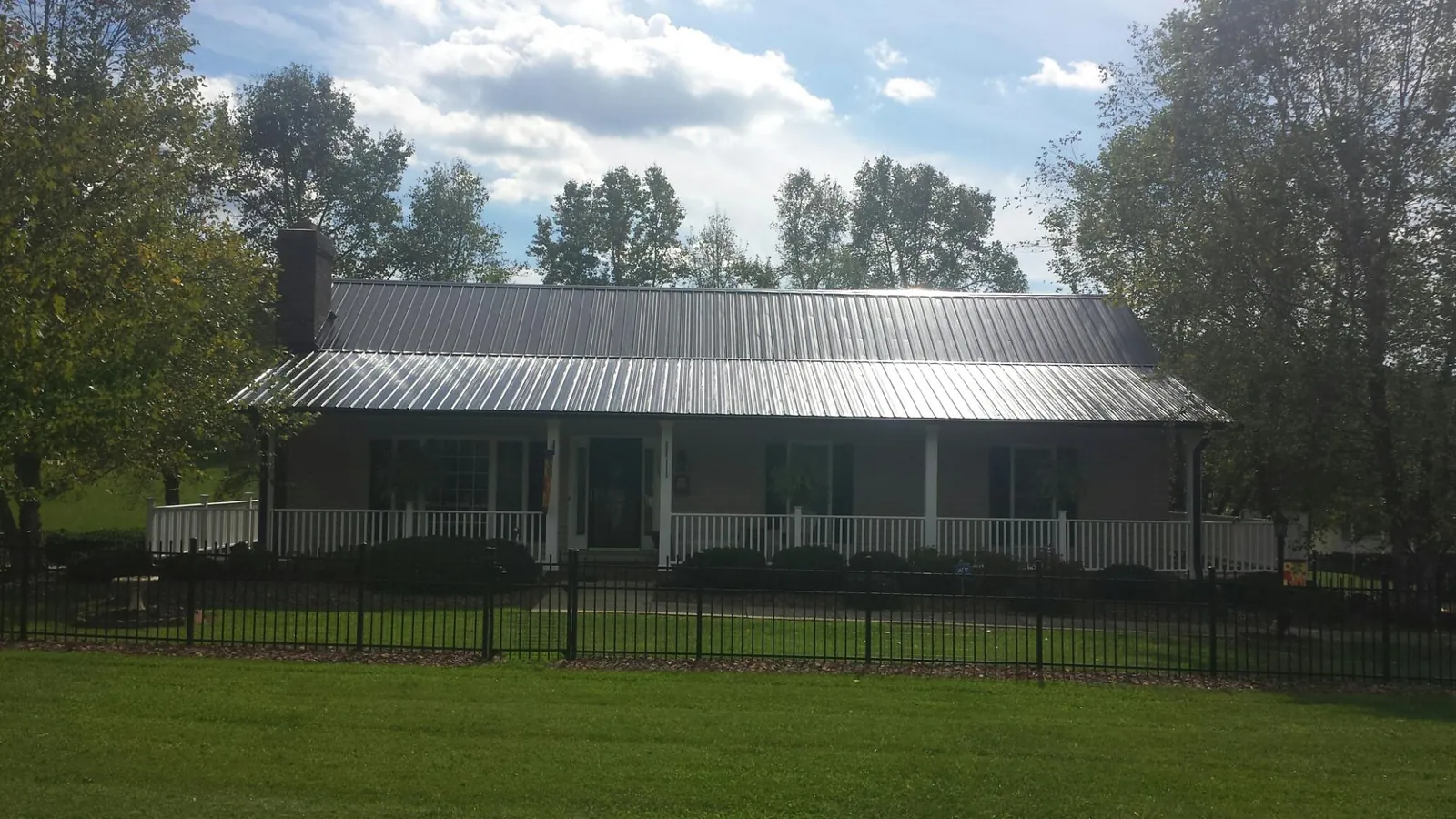 Gray metal roof on a brick ranch with a full width front porch — Gutter Guard Installation work by our crew in Tarboro