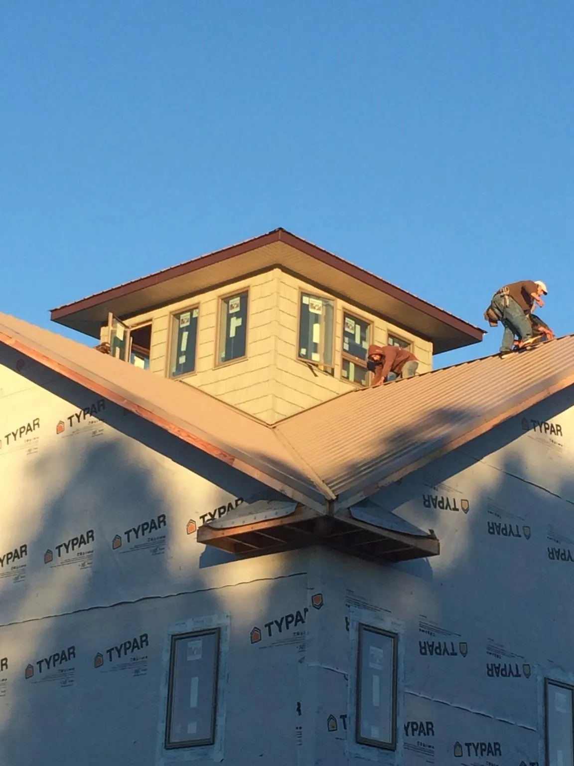 Roofers working around a rooftop cupola on a new metal roof at sunset — Roof Waterproofing in Tarboro by Roofing Brothers